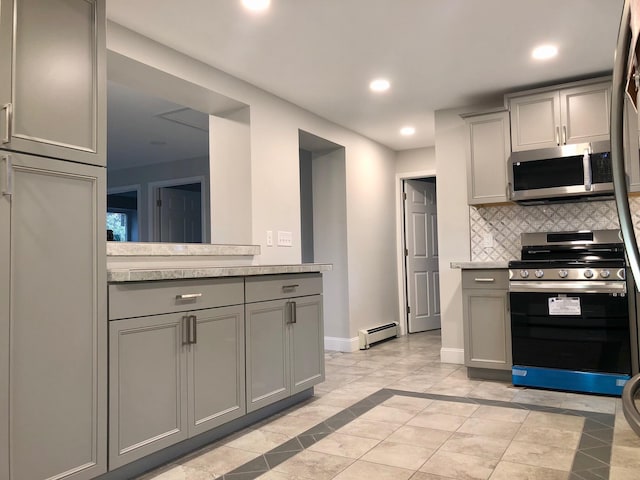 kitchen featuring tasteful backsplash, a baseboard radiator, light tile patterned flooring, gray cabinets, and stainless steel appliances