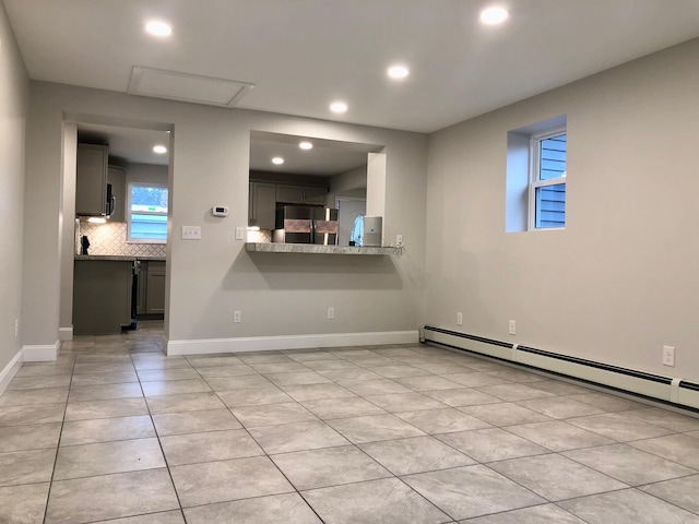 empty room featuring a baseboard heating unit and light tile patterned floors