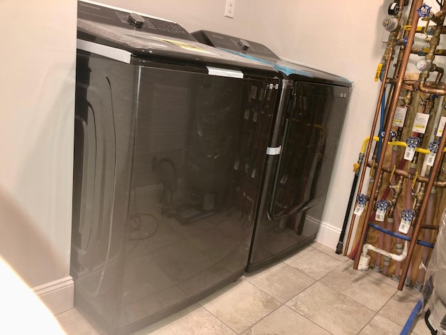 bathroom with independent washer and dryer, tile patterned floors, and a shower