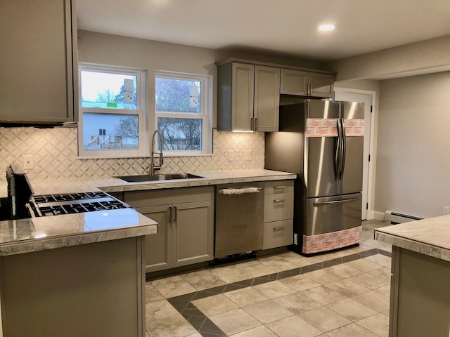 kitchen featuring a baseboard heating unit, light tile patterned floors, backsplash, sink, and stainless steel appliances