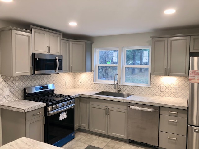 kitchen featuring backsplash, appliances with stainless steel finishes, sink, and gray cabinets