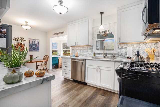 kitchen with light hardwood / wood-style flooring, hanging light fixtures, sink, white cabinetry, and appliances with stainless steel finishes