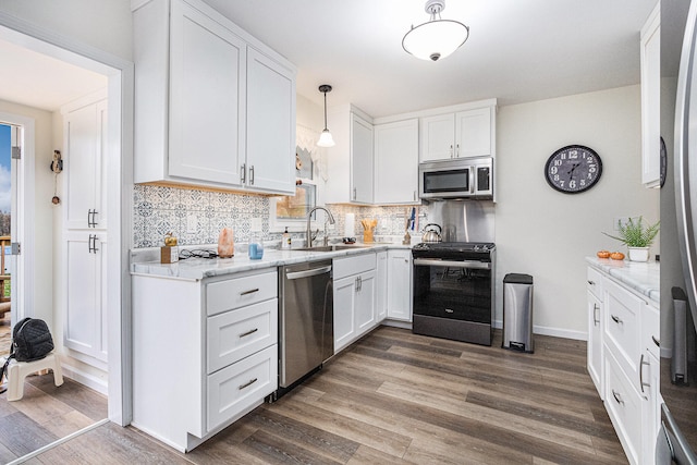 kitchen with dark wood-type flooring, white cabinetry, appliances with stainless steel finishes, and pendant lighting