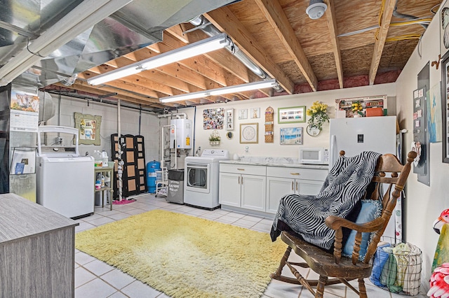 basement with water heater, washer and dryer, and light tile patterned flooring