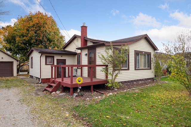 rear view of property with a garage, a yard, an outdoor structure, and a wooden deck