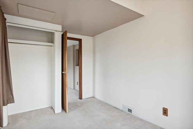 unfurnished bedroom featuring light colored carpet and a closet