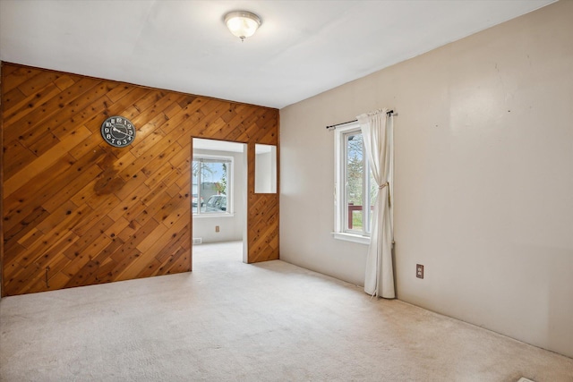 spare room featuring wooden walls and light carpet