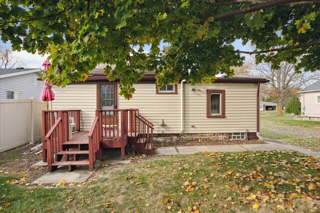 rear view of property featuring a wooden deck and a yard