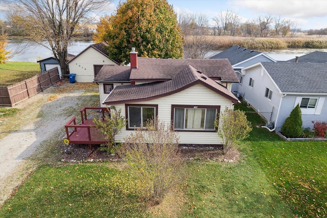 back of house with a deck with water view and a lawn