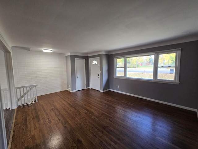 interior space with dark hardwood / wood-style flooring and brick wall