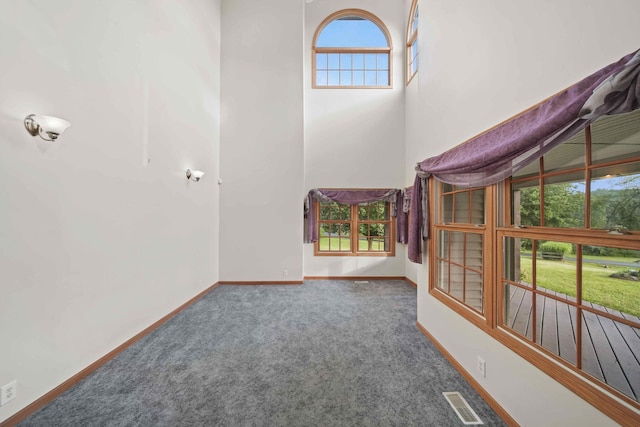 unfurnished living room with dark colored carpet and a wealth of natural light