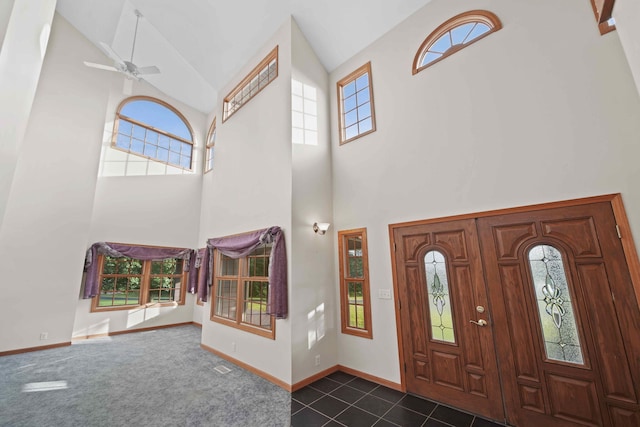 entryway with ceiling fan, a healthy amount of sunlight, high vaulted ceiling, and dark carpet