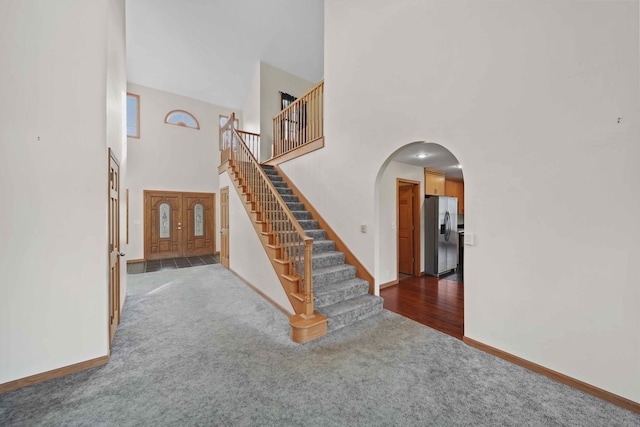 stairs with a towering ceiling and carpet floors