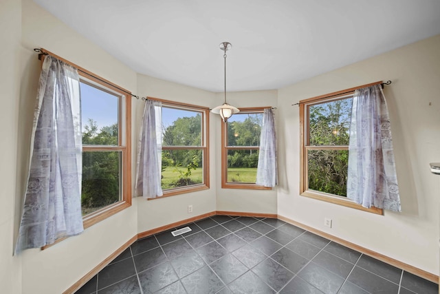 unfurnished dining area with a healthy amount of sunlight and dark tile patterned flooring