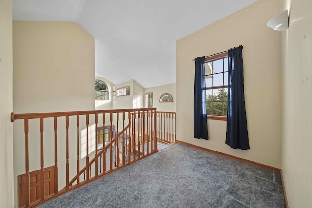 hallway with a wealth of natural light, vaulted ceiling, and carpet floors