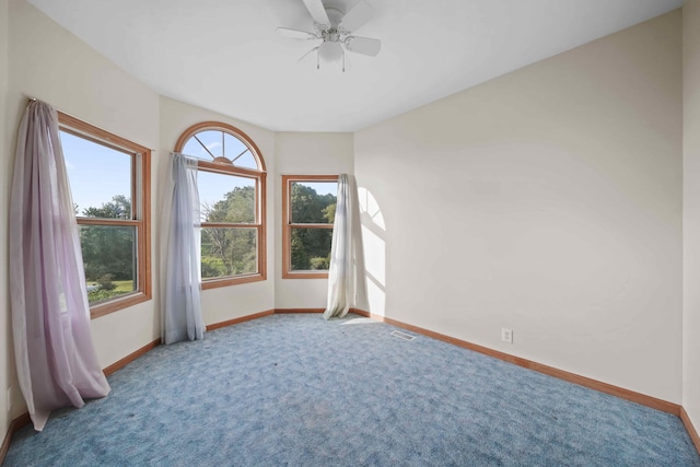 carpeted spare room featuring a wealth of natural light and ceiling fan