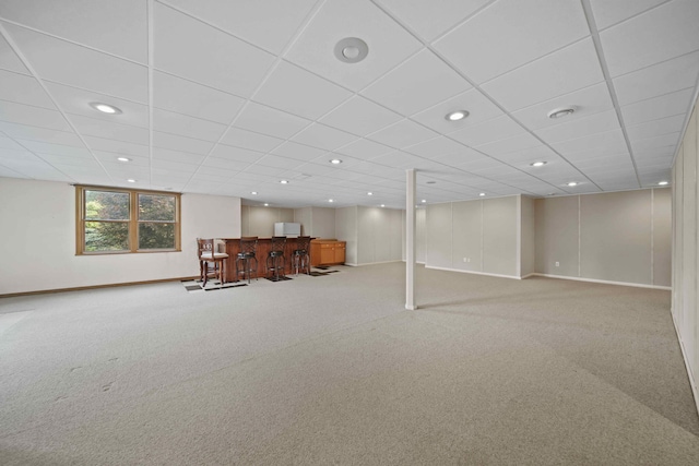 basement featuring bar area, carpet, and a drop ceiling