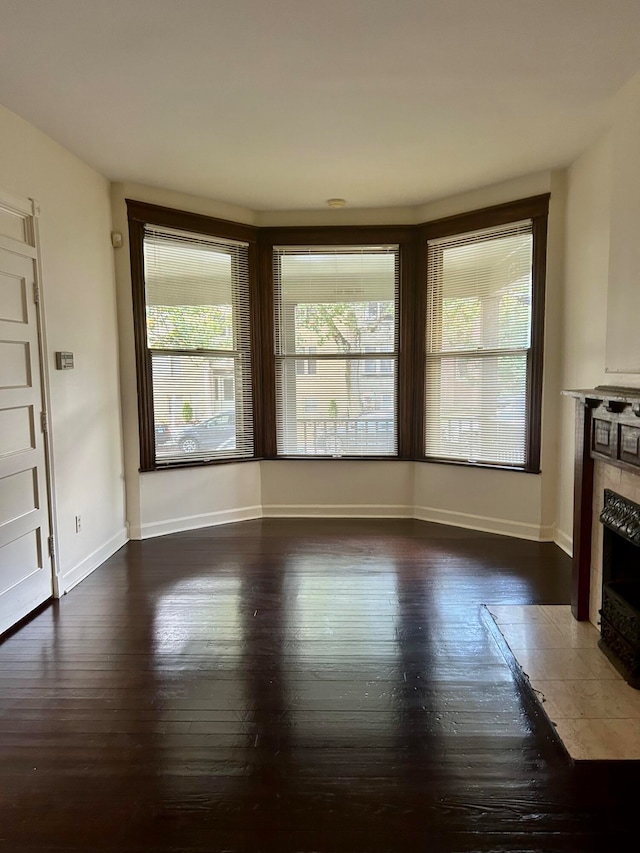 unfurnished living room with a tiled fireplace and dark hardwood / wood-style floors