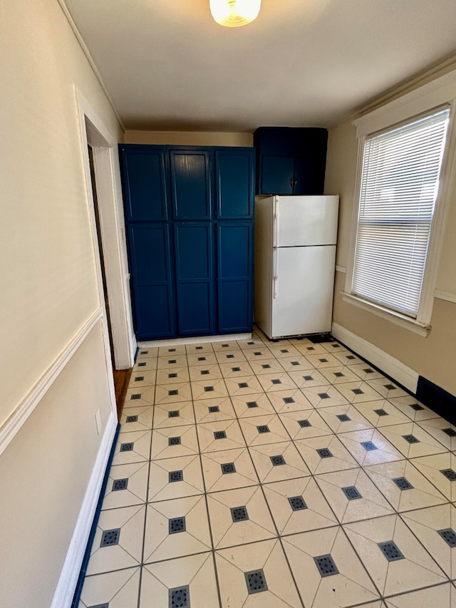 kitchen with blue cabinetry, white refrigerator, and light tile patterned floors