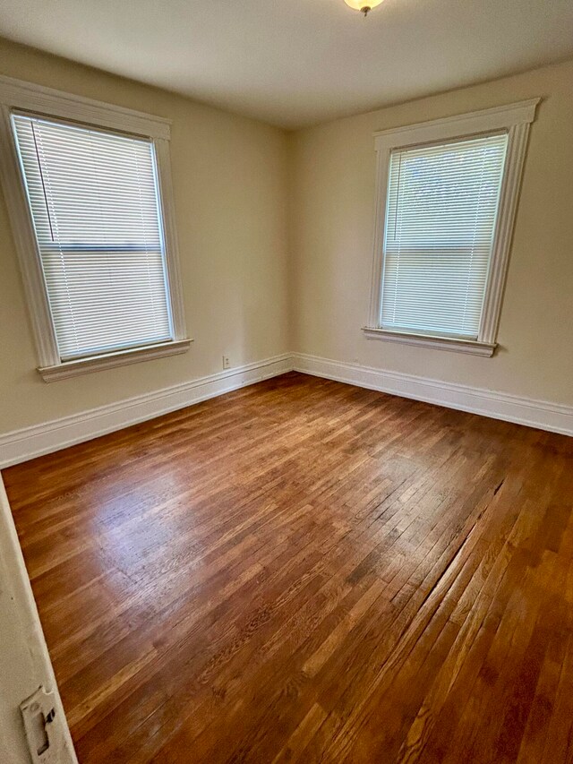 unfurnished room with a wealth of natural light and hardwood / wood-style flooring