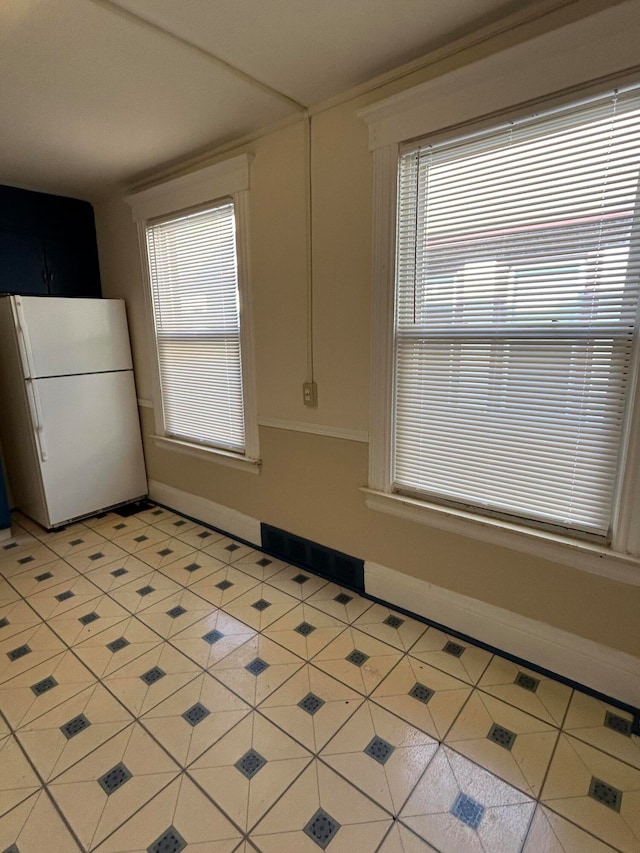 kitchen with white cabinetry, light tile patterned floors, and white fridge