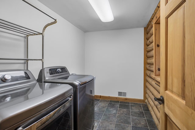 laundry area with dark tile patterned flooring and washer and dryer