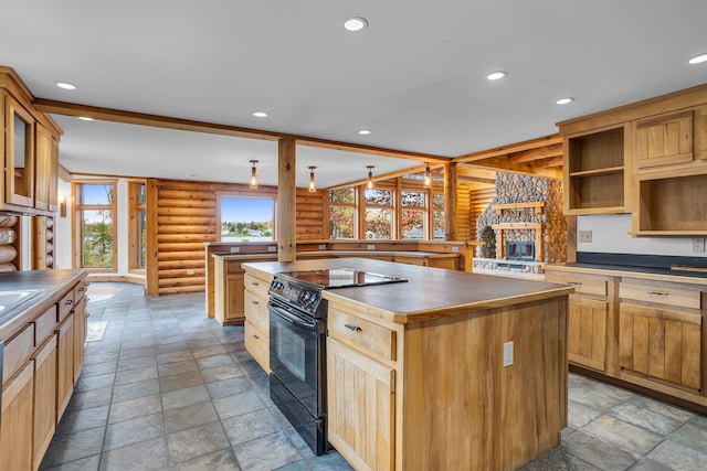 kitchen featuring a stone fireplace, black range with electric cooktop, rustic walls, and a center island