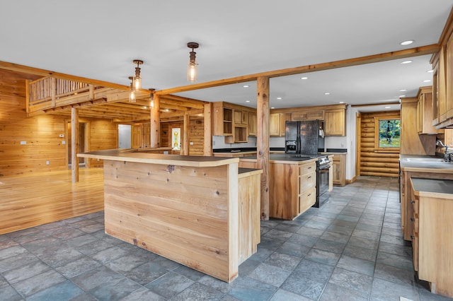 kitchen featuring sink, black appliances, a kitchen island, wooden walls, and pendant lighting