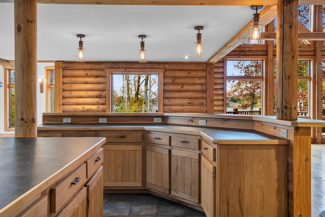 kitchen with pendant lighting, a wealth of natural light, and log walls