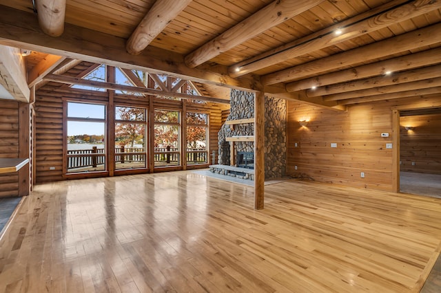 unfurnished living room featuring hardwood / wood-style flooring, wooden ceiling, beamed ceiling, a fireplace, and log walls