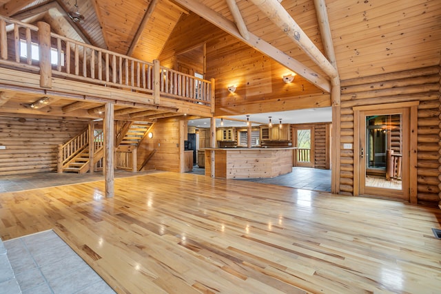 unfurnished living room with beam ceiling, high vaulted ceiling, wood ceiling, light hardwood / wood-style floors, and log walls