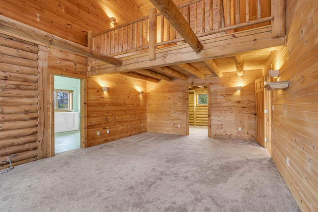 carpeted empty room featuring wood walls, wooden ceiling, and beamed ceiling