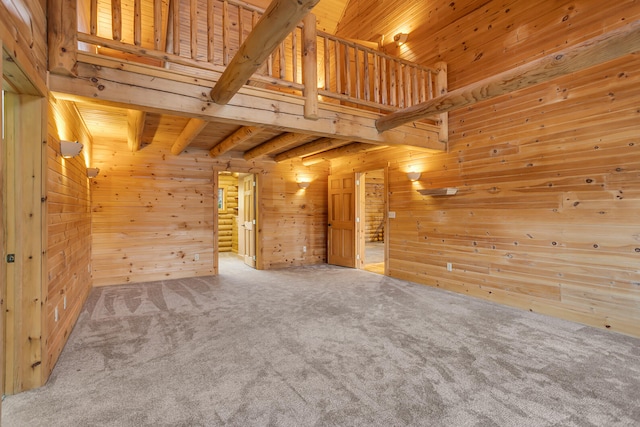 unfurnished living room with wood walls, beam ceiling, wood ceiling, and carpet