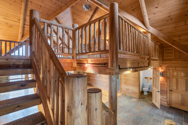 stairs with wood walls, wood ceiling, and vaulted ceiling with beams