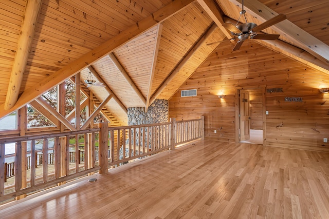 bonus room featuring wood walls, wood ceiling, beamed ceiling, ceiling fan, and light hardwood / wood-style flooring