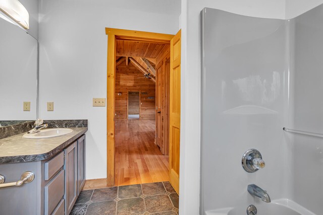 bathroom with wood walls, hardwood / wood-style flooring, vanity, and  shower combination