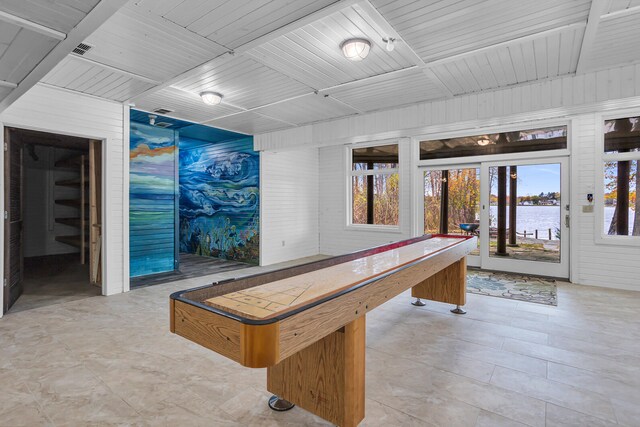 game room featuring wooden walls, a water view, and wood ceiling