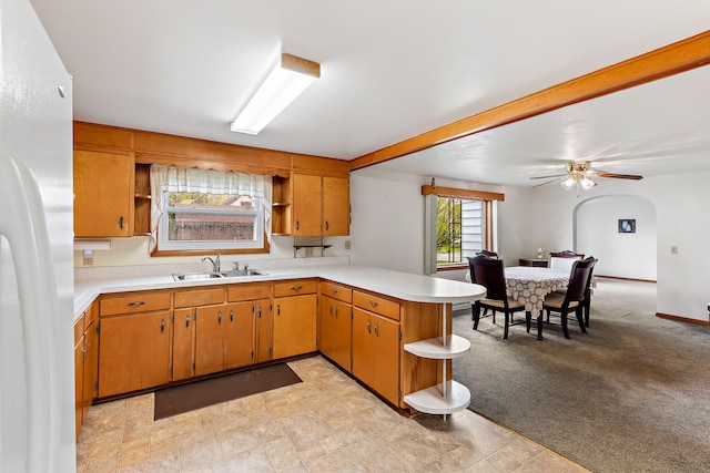 kitchen with kitchen peninsula, sink, light colored carpet, white refrigerator, and ceiling fan