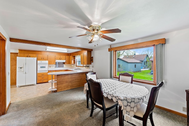 dining room with sink, light colored carpet, and ceiling fan