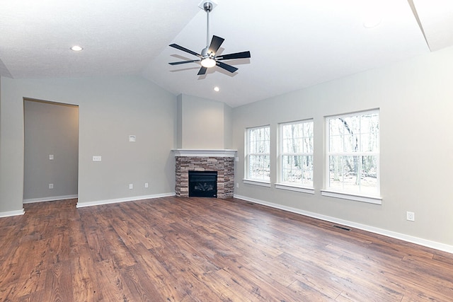 unfurnished living room featuring dark wood-type flooring, a stone fireplace, vaulted ceiling, and ceiling fan