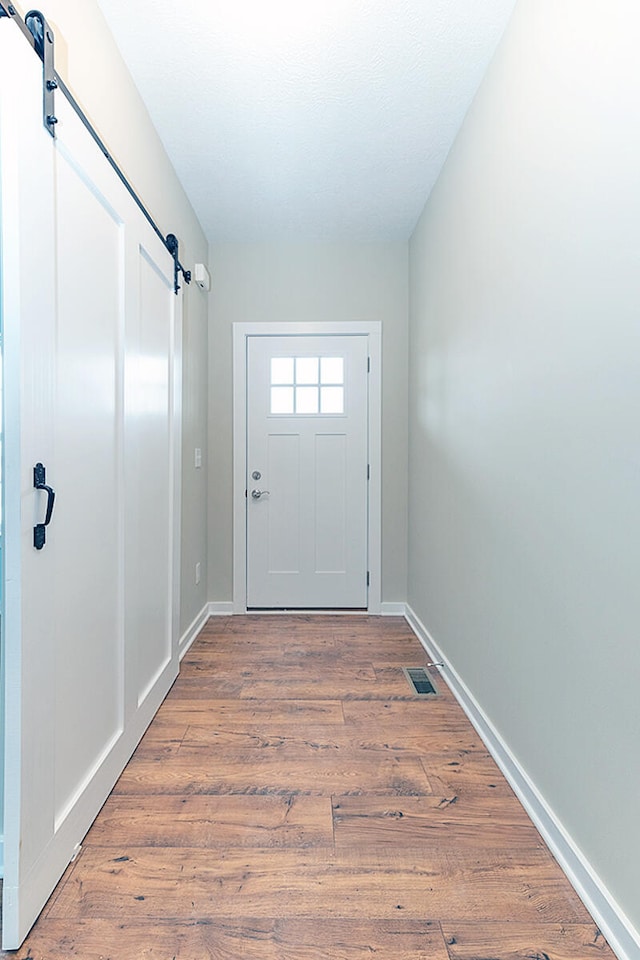 doorway with a barn door and wood-type flooring