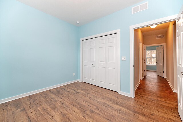 unfurnished bedroom featuring hardwood / wood-style floors and a closet