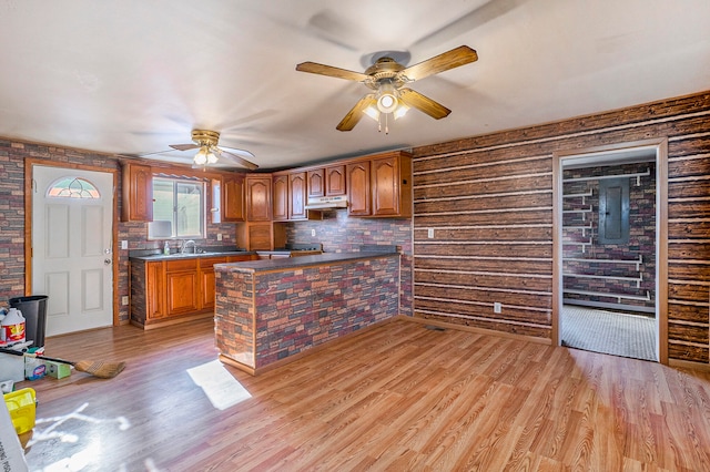 kitchen with wood walls, light hardwood / wood-style floors, sink, ceiling fan, and backsplash