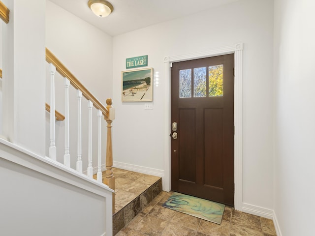 87 S Center St, Beulah, MI 49617 - foyer entrance with stone finish floors, baseboards, and stairway