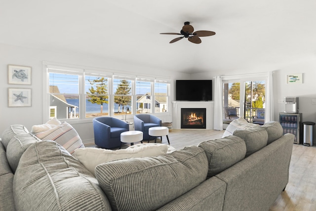 87 S Center St, Beulah, MI 49617 - living area with vaulted ceiling, light wood-style floors, ceiling fan, and a warm lit fireplace