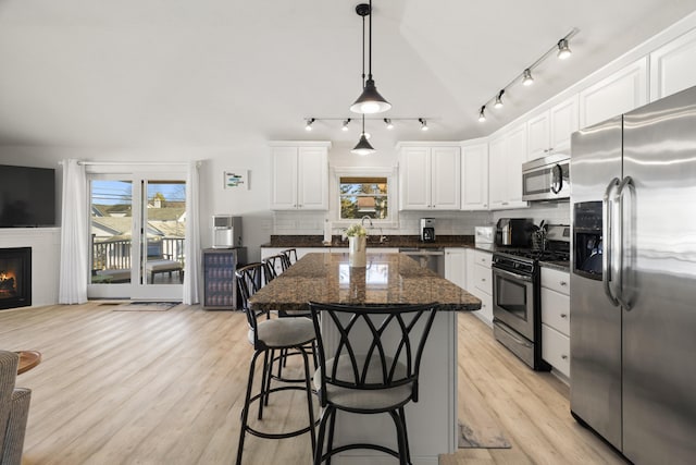 87 S Center St, Beulah, MI 49617 - kitchen with appliances with stainless steel finishes, tasteful backsplash, white cabinets, light wood-style floors, and a kitchen island