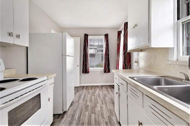 kitchen with white electric range oven, light wood-type flooring, white cabinetry, and sink