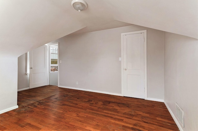 bonus room with dark wood-type flooring and vaulted ceiling