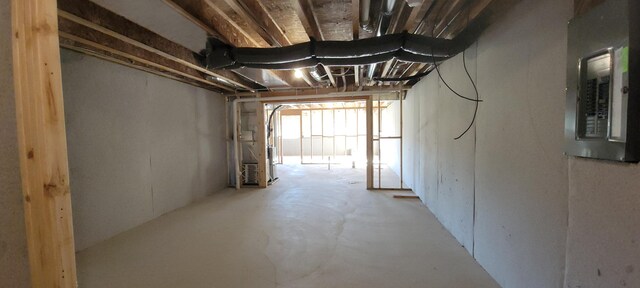 hall featuring electric panel, heating unit, and concrete floors