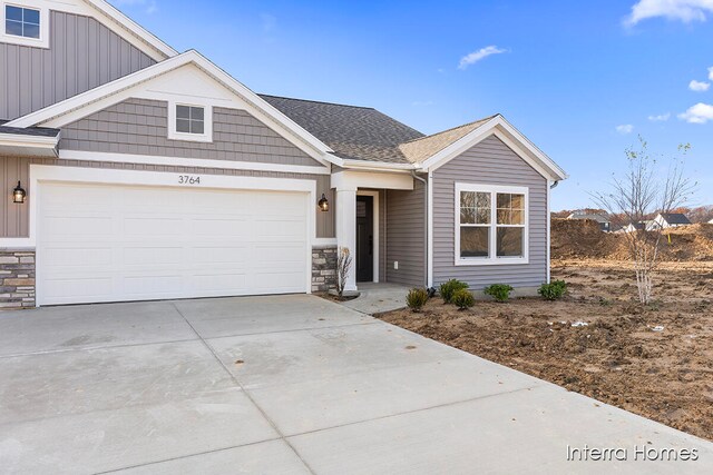 view of front of property with a garage, stone siding, roof with shingles, and driveway